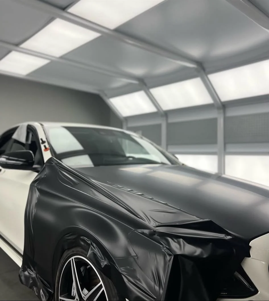 Film noir en cours de pose sur la carrosserie d’une Mercedes à l’atelier